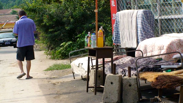Camponês passa em frente de loja com camas do lado de fora, onde os trabalhadores descansam na hora de almoço - Rodrigo Bertolotto/UOL