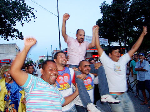 O prefeito Robério Oliveira é carregado por correligionários o chegar na Praça da Bandeira.